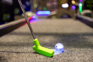 Blue illuminated putt mania golf ball next to mini golf putter.