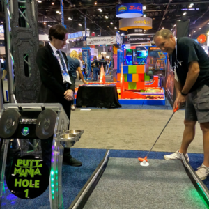 Woman in a suit observing while a man demos a mini golf hole