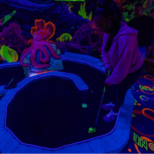 Woman putting on an indoor mini golf hole with Putt Mania.