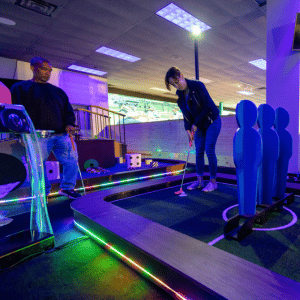 Two people on a soccer theme indoor mini golf hole with Putt Mania.