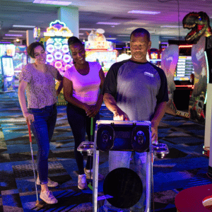 Two woman watching a man interact with a Putt Mania digital holemarker.