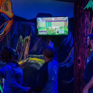 Three people on a glow golf course looking at a Putt Mania leaderboard.