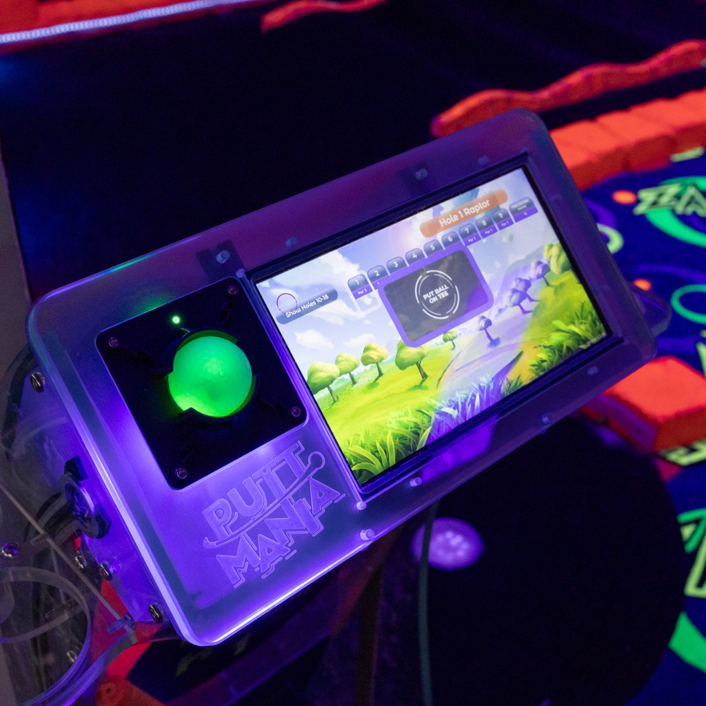 Putt Mania hole marker with touchscreen display and a green light up golf ball on the charger.