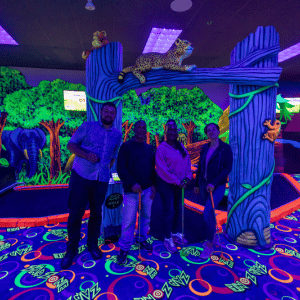 Four people standing in front of an indoor mini golf hole looking at the camera.