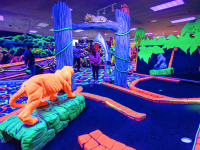 Woman putting off a jungle theme mini golf hole at an indoor mini golf course with Putt Mania tech.