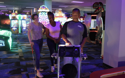 Two woman watching a man interact with a Putt Mania digital holemarker.