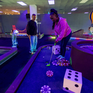 Two people on a casino theme mini golf hole with Putt Mania.