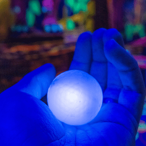 A hand holding a blue illuminated Putt Mania golf ball in it's palm.