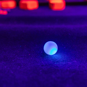 Blue illuminated Putt Mania golf ball on an indoor mini golf course.