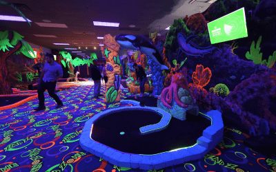 Three people at an indoor mini golf course with Putt Mania tech.