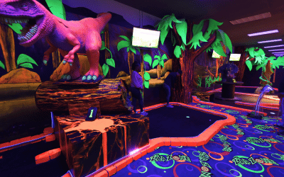 Two people on a t-rex theme mini golf hole with Putt Mania.