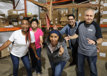 Group of five peole in a warehouse pretending to run from a model pterodactyl.