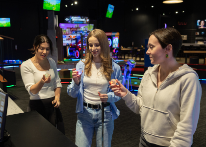 Three woman standing and holding LED-lit Putt Mania golf balls.